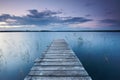 Colorful landscape with sky and wooden jetty pier reflected in the lake at evening