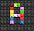 Colorful letter G from building lego bricks on black lego background. Lego letter M
