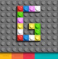 Colorful letter G from building lego bricks on gray lego background. Lego letter M