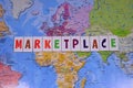 Colorful letters writing marketplace, world map background