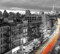 Colorful lights from cars driving down Bowery through New York City in a black and white street scene at night