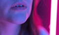 Colorful lips of a young woman in the light of neon close-up. Beauty and fashion in a nightclub