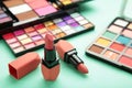 Colorful lipsticks and palette shadow on mint background. Makeup