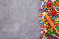 Colorful lollipop and different colored round candy on grey concrete background