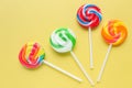 Colorful lollipops, different colored round candy on sticks on yellow background. Royalty Free Stock Photo