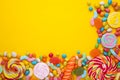 Colorful lollipops and different colored round candy on yellow background Royalty Free Stock Photo