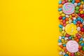 Colorful lollipops and different colored round candy on yellow background Royalty Free Stock Photo