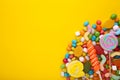 Colorful lollipops and different colored round candy on yellow background Royalty Free Stock Photo