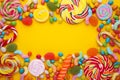 Colorful lollipops and different colored round candy on yellow background Royalty Free Stock Photo