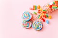 Colorful lollipops swirls on sticks in glass bottle. Striped spiral multicolored candy on pink background, top view Royalty Free Stock Photo