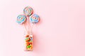 Colorful lollipops swirls on sticks in glass bottle. Striped spiral multicolored candy on pink background, top view Royalty Free Stock Photo