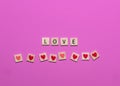 Colorful love wooden block game tiles with hearts on a pink background