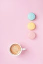 Colorful macaron and cup of coffee on pastel pink background top view. Cozy morning breakfast. Fashion flat lay. Sweet macaroons.