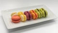 A colorful macaroon collection on a white plate, indulgent sweetness