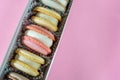 Colorful macaroon cookies in a cardboard box on a pink background. Copy space Royalty Free Stock Photo