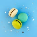 Colorful macaroon flat lay on bright blue background with confetti. French delicious dessert. Square social media template