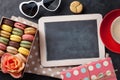 Colorful macaroons, coffee and blackboard