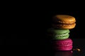 Colorful macaroons on dark black background. Variety of french almond macaron cookies in pile