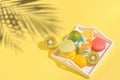 macaroons with lemon, lime  and kiwi on white tray on sulit yellow background with shadows . Summer refreshment concept Royalty Free Stock Photo