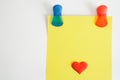 Colorful Magentic pins or clips hold a yellow piece of paper with a red heart on a magnetic board or refrigerator door. Blank is a