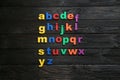 Colorful magnetic letters on black background, flat lay. Alphabetical order