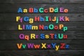 Colorful magnetic letters on black wooden background. Alphabetical order Royalty Free Stock Photo