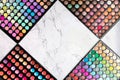 Colorful make-up eyeshadow palettes on white marble background. Rhombus shape frame