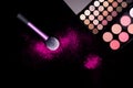 Colorful makeup palette and pink big brush to apply powder on pure black background. Professional makeup equipment. Royalty Free Stock Photo