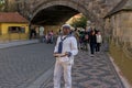 A colorful man invites tourists to visit the Charles Bridge Museum in Prague.