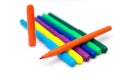 Colorful markers lying in a row on a white background. Opened orange marker lies on top of the other ones. Art and education