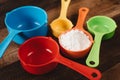 Colorful measuring cups with flour on wooden table