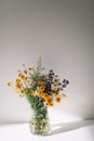 Colorful midsummer bunch of wildflowers. Bouquet of wild natural flowers in a vase on the table, selective focus.