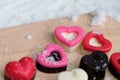 Colorful milk chocolates heart on wooden plate and snow.