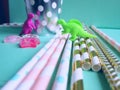 Colorful mint, pink and golden drinking straws for beverages with dinosaur toys. Party theme composition