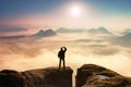 Colorful misty morning in rocks. Tourist in dark cloths on rock empire shadowing eyes