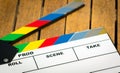 Colorful movie clapboard lying on wooden surface as seen from above