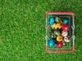 Colorful of multi Easter eggs in red shopping cart on green grass the background is wooden board Royalty Free Stock Photo