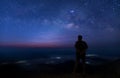 Colorful night sky with stars and silhouette of a standing man on the stone. Blue milky way with man on the mountain. High Rocks. Royalty Free Stock Photo