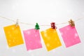 Colorful note papers hanging rope with mini Christmas wooden clamps on snow background Royalty Free Stock Photo