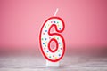 Colorful number 6 birthday cake candle on a pink background