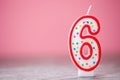 Colorful number 6 birthday cake candle on a pink background