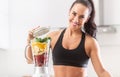 Colorful nutrition of spinach, oranges, bananas and strawberries put into a blender by a fit woman