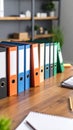 Colorful office binders lined up on a wooden desk in an organized office setting ready for work Royalty Free Stock Photo