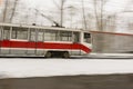 Colorful orange fast moving tram in blurred street with snow