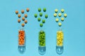 Colorful, orange, green, yellow pills spill out of the transparent bottle on the blue background. Royalty Free Stock Photo