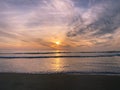 Colorful orange ocean beach sunset with deep clouded sky. Royalty Free Stock Photo