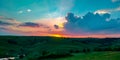 Colorful orange sunset on green hills with a calming blue sky durig a warm summer