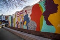 a colorful orange, yellow, blue and pink wall mural with silhouettes of people and the words Be Love at the King Center in Atlanta