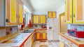 Colorful orange and yellow kitchen design with fridge, red Oven Grill, sink and white walls