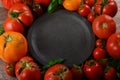 Colorful organic tomatoes - blue tomatoes around an empty clay plate. Tomatoes background Royalty Free Stock Photo